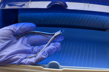 hand in a blue medical glove with manicure and pedicure forceps after sterilization in ultraviolet...
