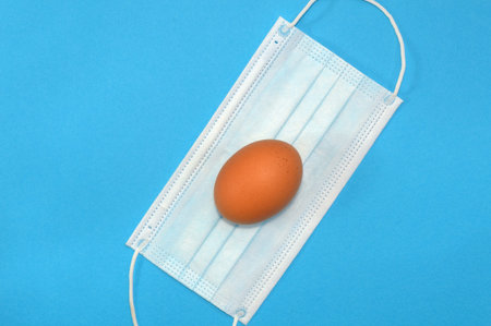 Easter egg and medical mask on blue background, coronavirus pandemic concept and holiday in...