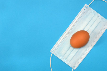 Easter egg and medical mask on blue background, coronavirus pandemic concept and holiday in...