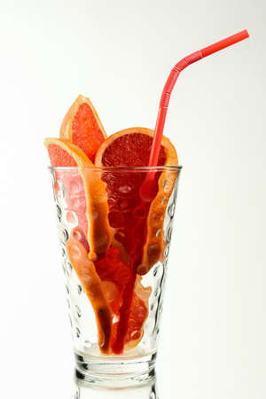 Pieces of grapefruit with a red drinking straw in a glass. Make a healthy and delicious citrus drink that's high in vitamins.の写真素材