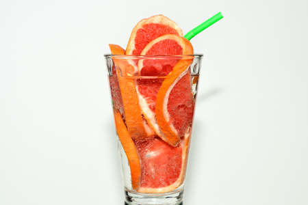 The sliced grapefruit in a glass with carbonated water and red cocktail tube.の写真素材