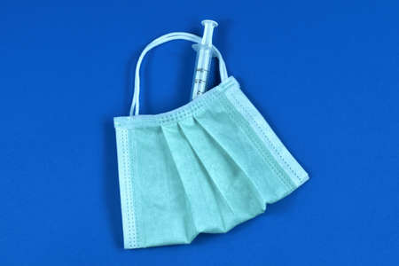 Medical syringe and face mask in the form of a bag with handles. Vaccination and treatment strategy during the virus pandemic.の写真素材