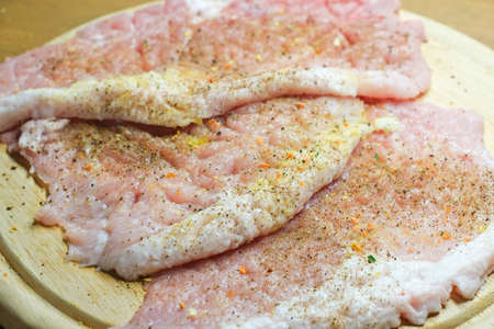 Pork meat spiced with seasoning. Pork chop on kitchen cutting board ready to fry.の写真素材