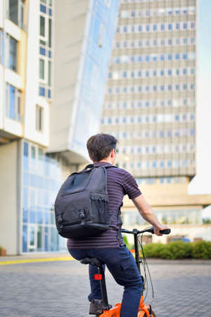Young man with backpack, cyclist on a bicycle while biking around the city. The student riding to work or study by bike.の写真素材