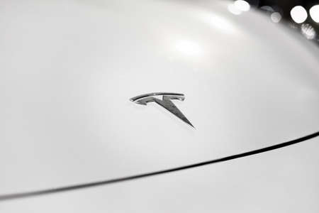 The insignia of Tesla Motors as seen on a hood of white electric vehicle. Tesla company logo on the front bonnet of electric car: Riga, Latvia - September 22, 2021.のeditorial素材
