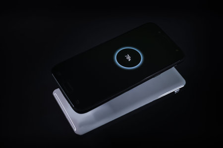 Smartphone while wireless charging from a charger on black background