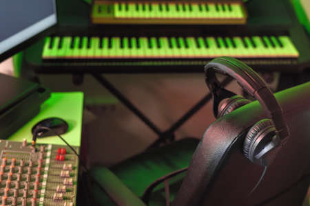 Professional headphones in a recording studio against the background of blurry synthesizers and musical equipment. Sound engineer and producer workplace in music recording studio.の写真素材