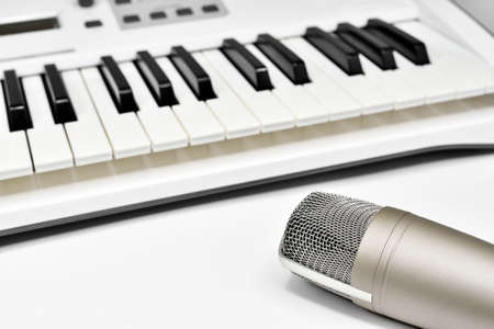 Professional studio microphone against blurred synthesizer keyboard background. Professional studio gear for voice and music recording.の写真素材