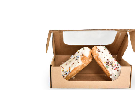 Eclairs in a cardboard box on a white background. Disposable protective cardboard box with sweet...