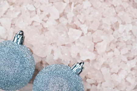 Top view of Christmas decorative silver blue balls on blurred background of ice pieces with copy space for greeting text.の写真素材