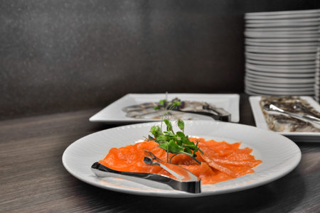 Salted salmon garnished with herbs and leaves served in a white plate.の写真素材