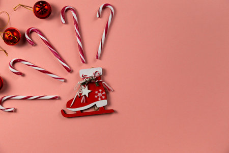 Top view of Christmas bells with many candy cane on pastel pink background.Holiday festive...