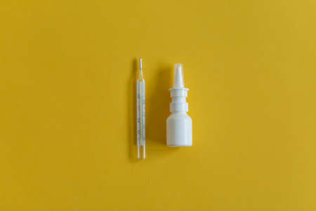 nasal drops, thermometer, various lie on the table, top view medicines, on a yellow background, FlatLayの写真素材
