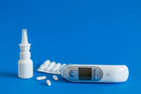 FFP3 mask, nasal drops, thermometer, tablets, various medicines lie on the table, top view, on a blue background, FlatLayの写真素材
