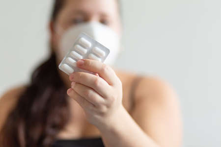 Girl in a mask on a white background holding a tablets, medical themeの写真素材