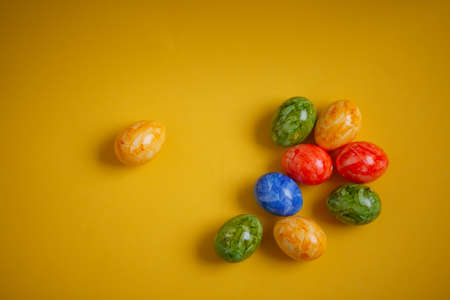 Multicolored easter eggs on a yellow background, top view, place for textの写真素材