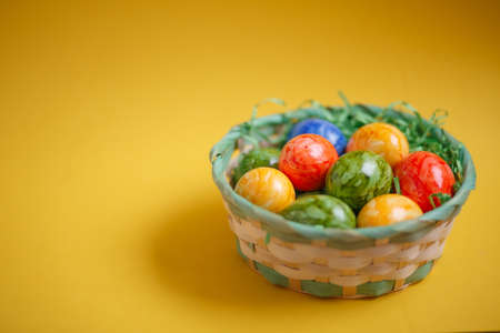 Easter card. Flat lay composition with easter eggs in a basket on yellow background. Top viewの写真素材