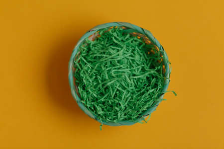 Green basket for easter eggs on a yellow background. Top viewの写真素材
