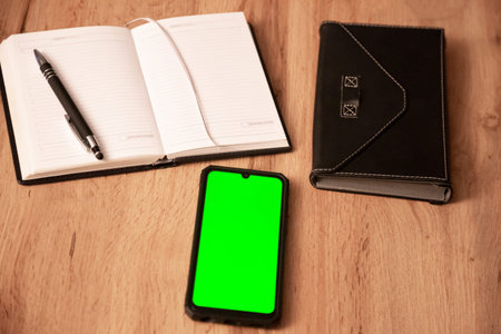 Mobile phone and notebook on wooden table, Realistic smartphone mockup, work from home, home office, cover from e-bookの写真素材