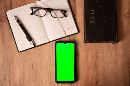 Mobile phone and notebook on wooden table, Realistic smartphone mockup, work from home, home office, cover from e-bookの写真素材