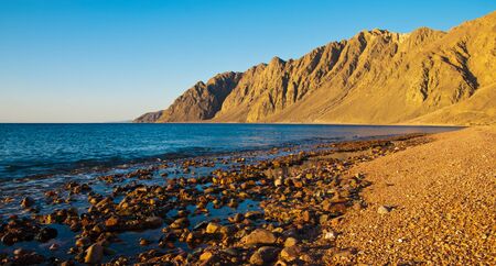 Egypt, Dahab, Mounts on sunset, sunrise and beach with stones, pebble, sea.の写真素材