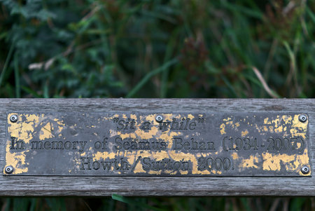 Memorial bench "sit a while" in memory of Seamus Behan along Howth Cliff Walk Path, Howth, Dublin, Irelandのeditorial素材