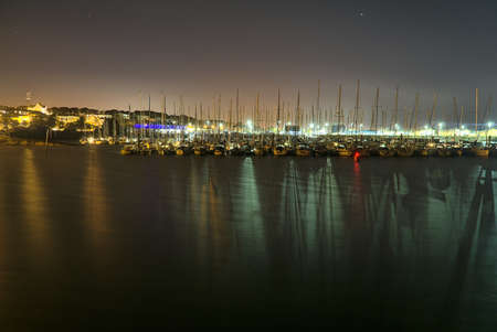 Amazing night view of a lot of boats and yachts at Howth harbor, Dublin, Ireland. Colorful lights spectacle with reflection in waterの写真素材