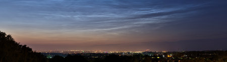 Beautiful panoramic view of very rare noctilucent clouds and stars shining through them seen in Dublin, Ireland on summer solstice of 2021 before midnight. Details of NLC. Night shining panoramaの写真素材
