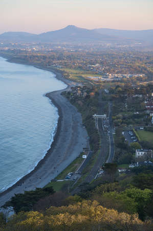Beautiful aerial-like evening view of Killiney Beach, coastal line and railway seen from Killiney Hill during golden hour, Dublin, Ireland. Soft and selective focusの写真素材