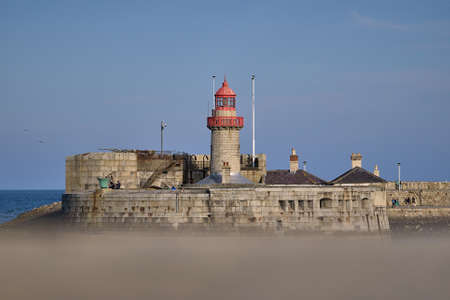 Beautiful creative evening view of red East Pier lighthouse in Dun Laoghaire harbor seen from West Pier, Dublin, Ireland. Copy space. Soft and selective focusの写真素材