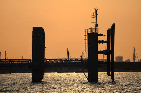 Dublin, Ireland - June 21, 2021: Beautiful telephoto evening view of wingwalls, dolphins and transfer span bridge of St Michael pier ferry terminal in Dun Laoghaire harbor during sunset. Soft focusのeditorial素材