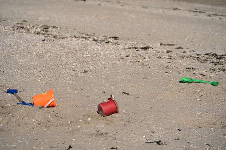 Closeup view of colorful children plastic toys left or forgotten at Sandymount Beach after messy sea activities during lowest tide, Dublin, Ireland. Conceptual. Copy space. Soft and selective focusの写真素材