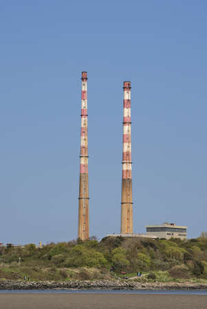 Beautiful closeup vertical bright view of iconic Poolbeg CCGT station chimneys against clear blue sky seen from Sandymount Beach, Dublin, Ireland. Soft colorsの写真素材
