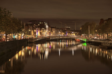 Dublin, Ireland - November 13, 2021: Beautiful evening view of River Liffey and illuminated Ha'penny Bridge. Refurbished 19th-century cast-iron span & city symbolのeditorial素材