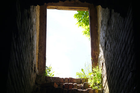 The old ruined exit from the basement. Brick steps rising upward. Blue sky with white clouds.