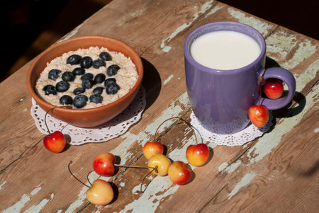 Oatmeal porridge with blueberries and wooden spoon on a blue towelの写真素材