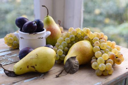 PEars, plums and grapes on a shabby wooden sufrace, still life for autumn harvestの写真素材