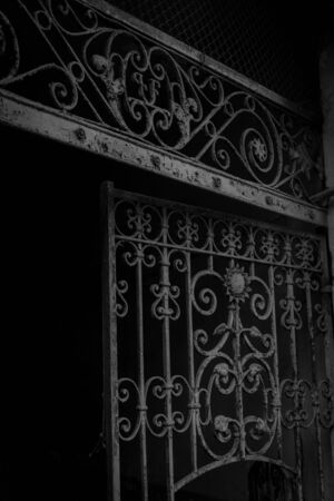 Black and white picture of old iron gate detail, curved, with initials.の写真素材