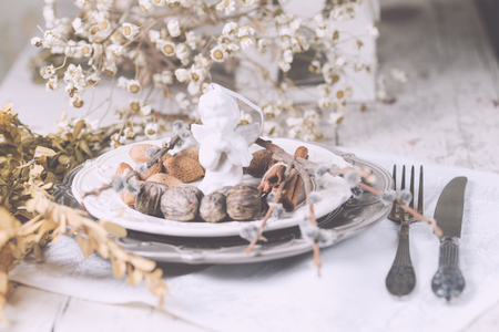 Two tone plates white and grey in a vintage style, served for Christmas dinner with vintage cutlery and white napkin on a shabby white table with spices and other decorations.の写真素材