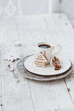 Shabby chic style coffee cup and plate with gingerbread house cookie, cinnamon sticks and other decorations for Christmas moodの写真素材