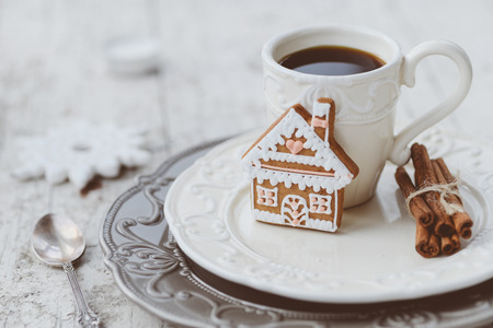 Shabby chic style coffee cup and plate with gingerbread house cookie, cinnamon sticks and other decorations for Christmas moodの写真素材