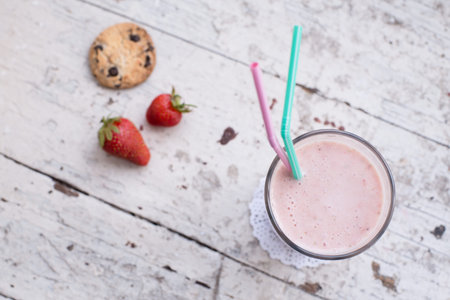 Banana and strawberry delicious smoothie with yogurt, on a wooden shabby background with two straws...