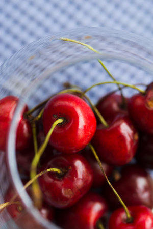 summer juicy berries - red cherries in a glass bowl, close up on a wooden table