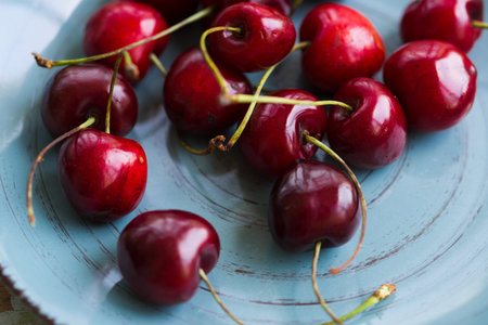 Blue ceramic shabby plate full with dark red juicy cherries