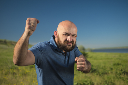 Caucasian white man with beard and mustache showing fists. blue skyの写真素材