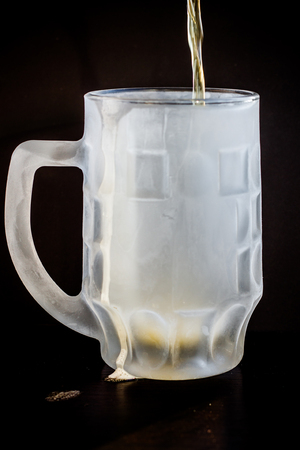frozen beer glass with beer on black backgroundの写真素材