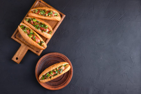 Hot dog, hot dog with pickled cucumbers, jalapeno peppers, carrots, greens on a black backgroundの写真素材