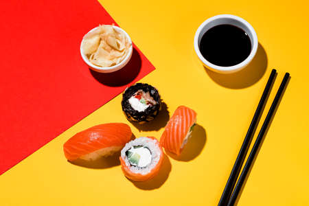 Sushi and rolls on a colored background, soy sauce, ginger. With a hard lightの写真素材