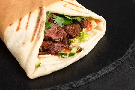 Burrito, Mexican beef burrito on a black background, side viewの写真素材