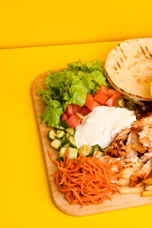 Shawarma with chicken on a wooden board, side view yellow background
